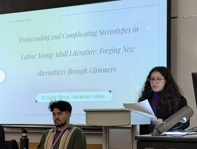 Jizelle Villegas presents her research paper, displayed on a large presentation screen behind her.